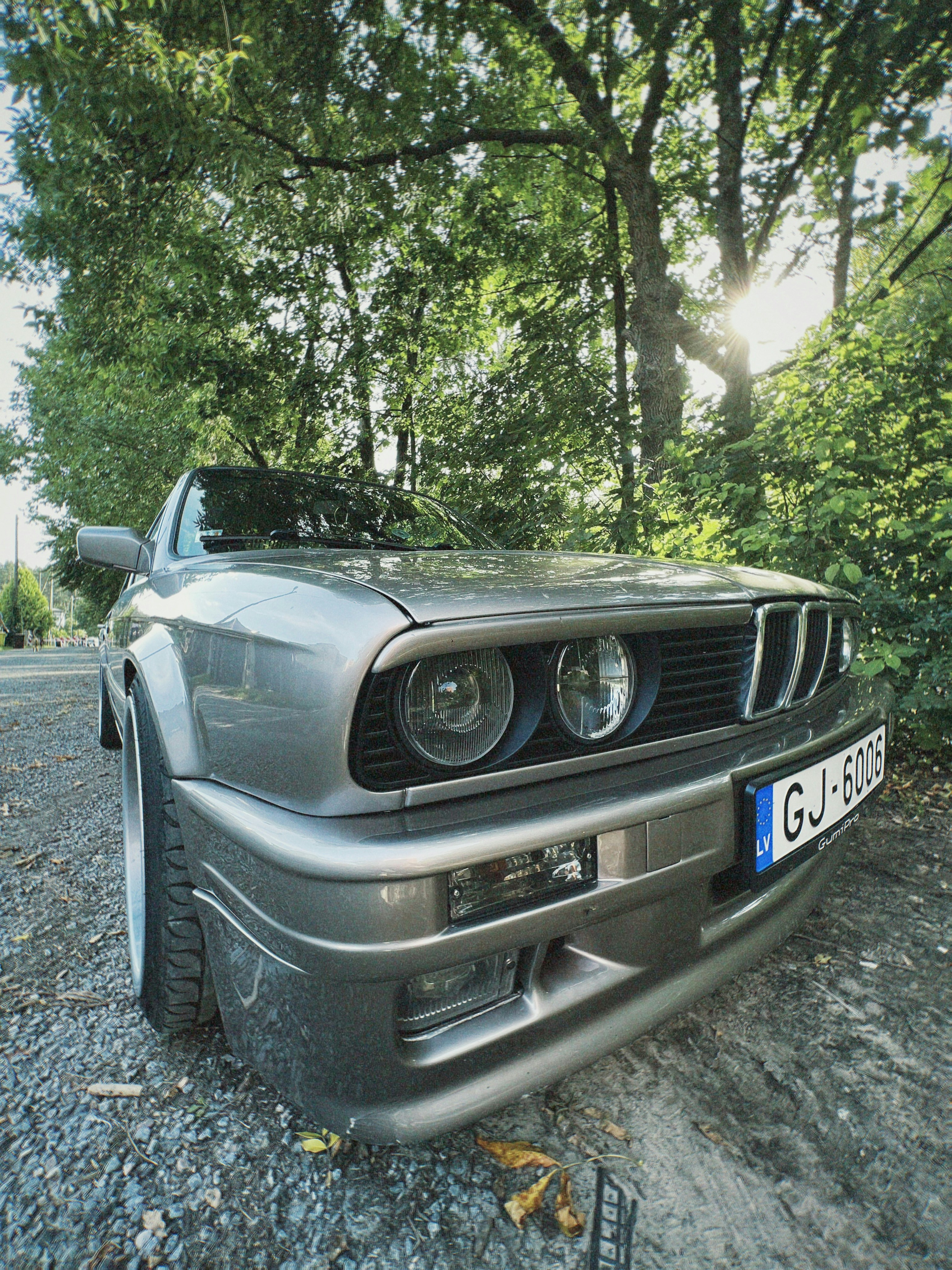Grey classic car parked on gravel road