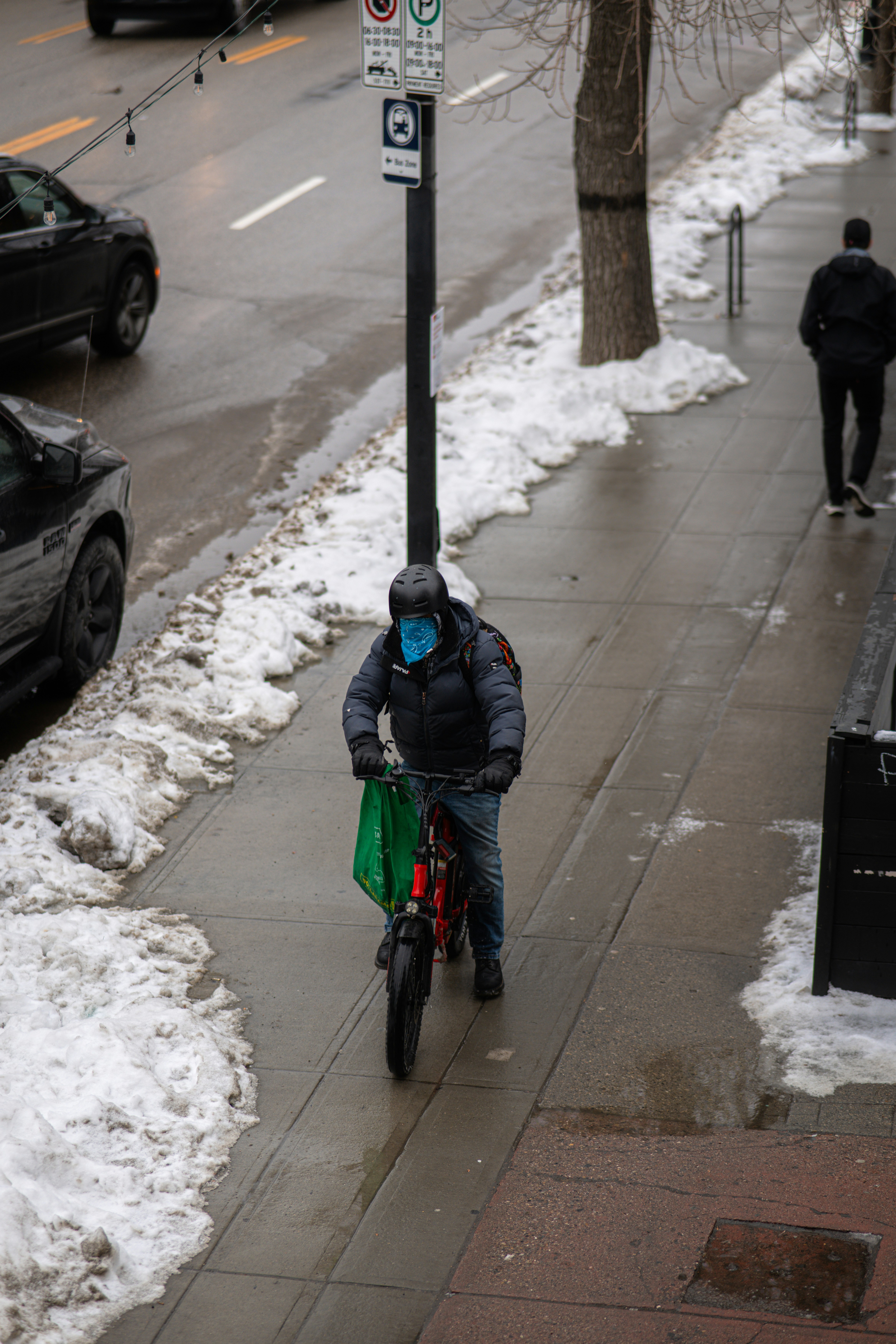 Man rides bicycle on snowy city sidewalk