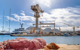 Boats and cranes in a sunny harbor.