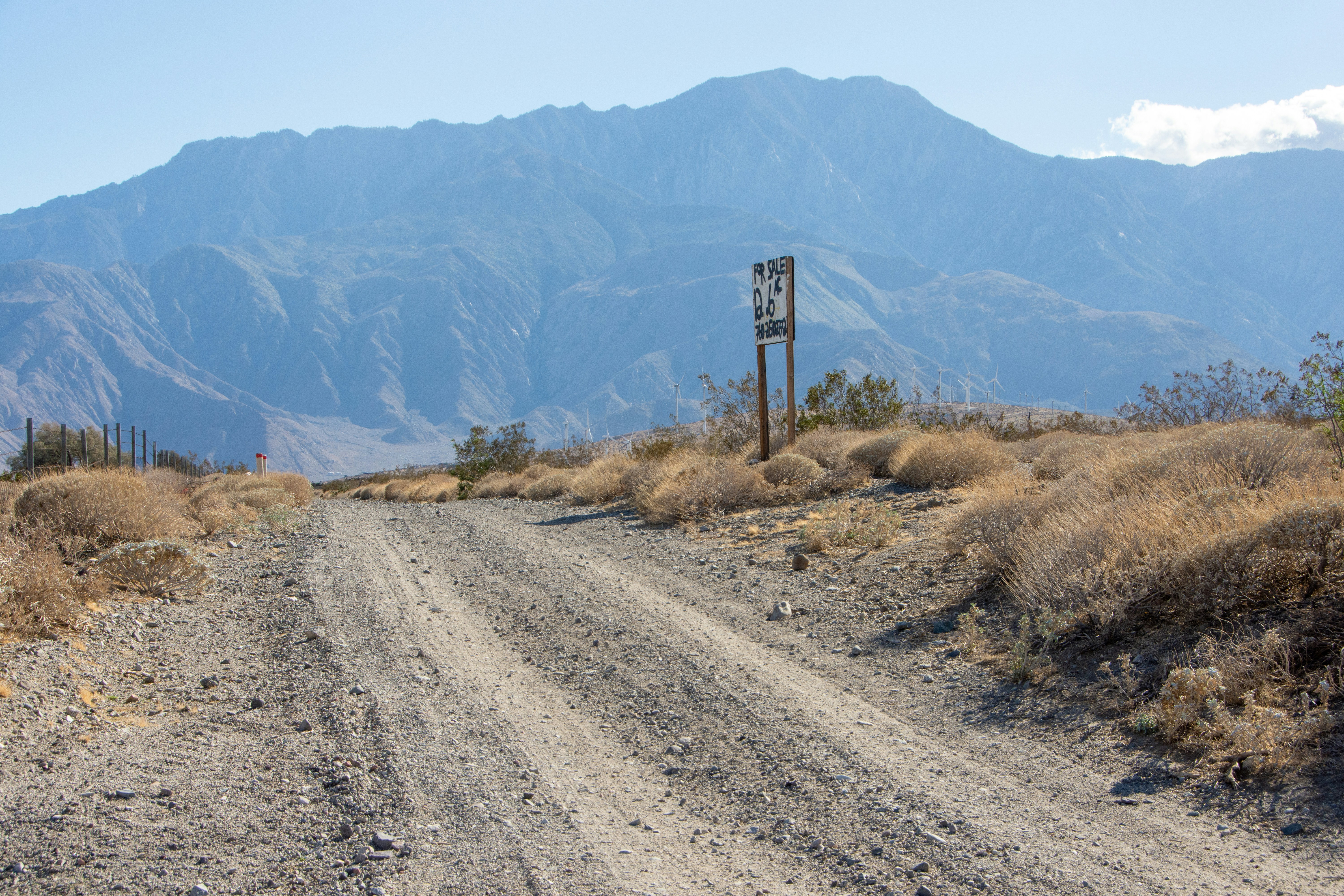 Dirt road leads to distant mountains under blue sky