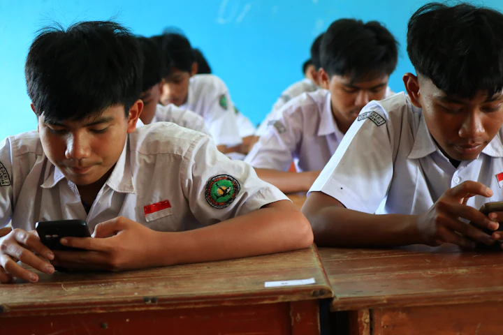 Students in uniform using smartphones in a classroom