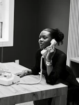 Woman talking on a vintage telephone at a desk
