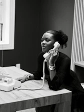 Woman talking on a vintage telephone at a desk