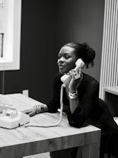 Woman talking on a vintage telephone at a desk