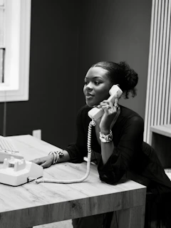 Woman talking on a vintage telephone at a desk