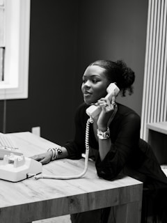 Woman talking on a vintage telephone at a desk