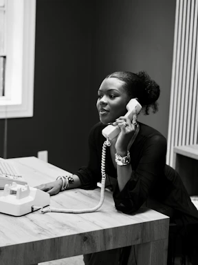 Woman talking on a vintage telephone at a desk