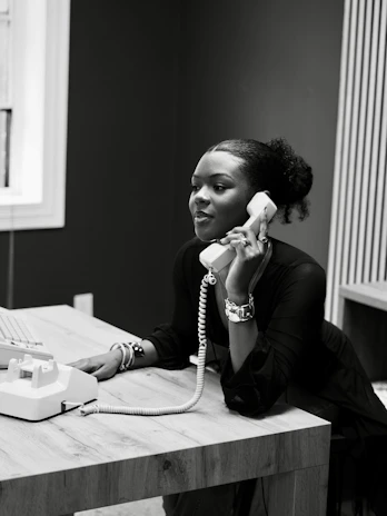 Woman talking on a vintage telephone at a desk