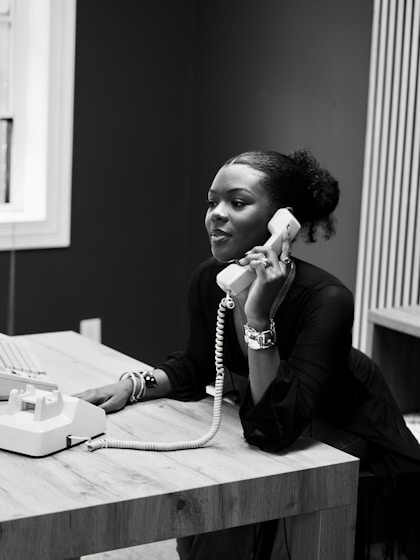 Woman talking on a vintage telephone at a desk