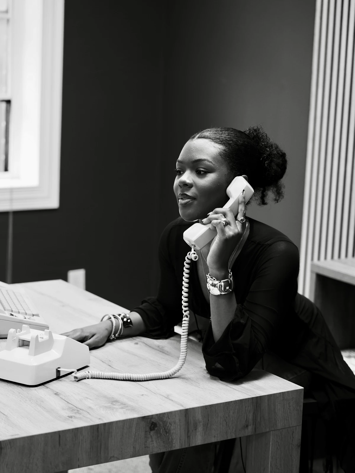 Woman talking on a vintage telephone at a desk