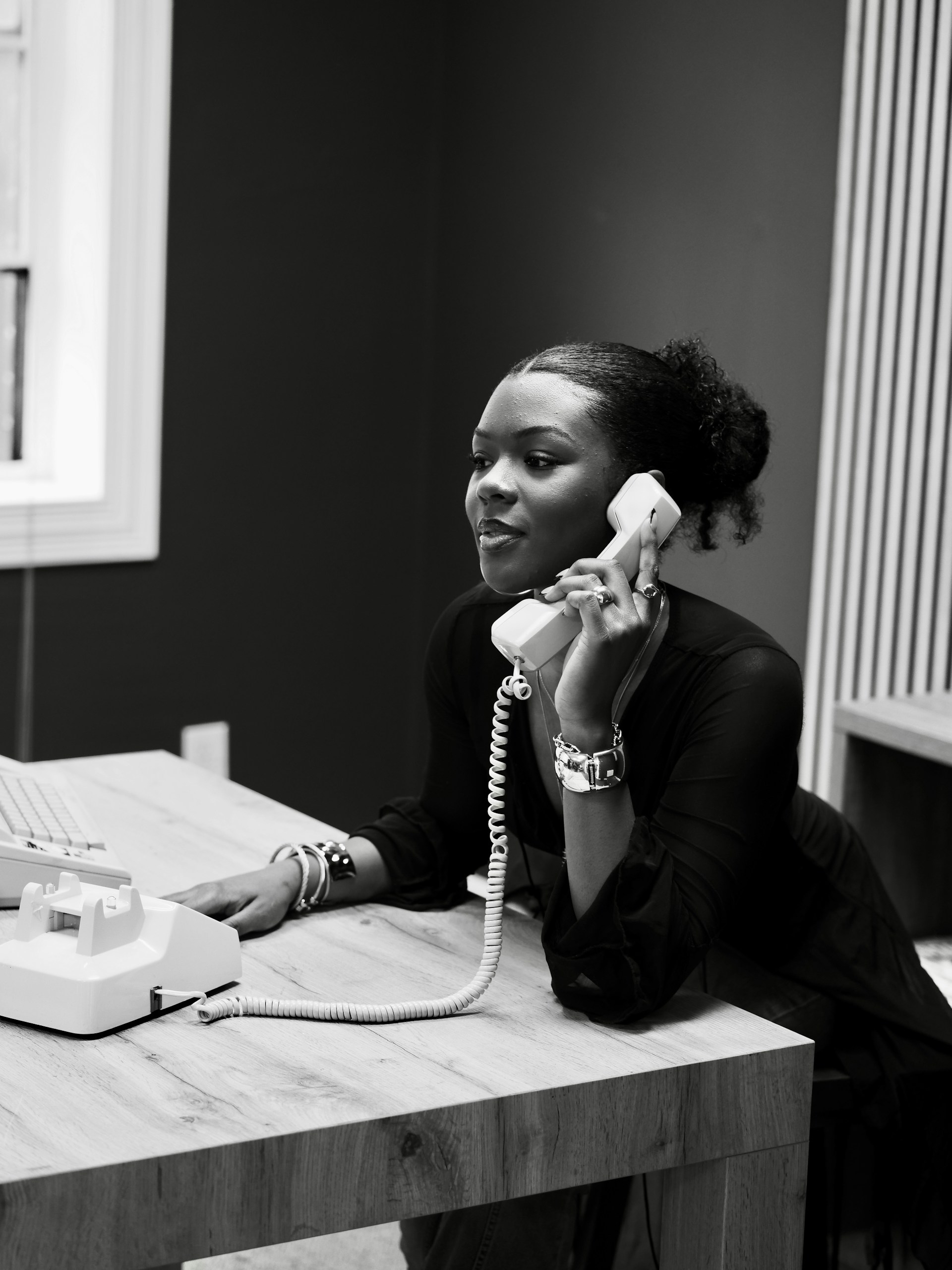 Woman talking on a vintage telephone at a desk