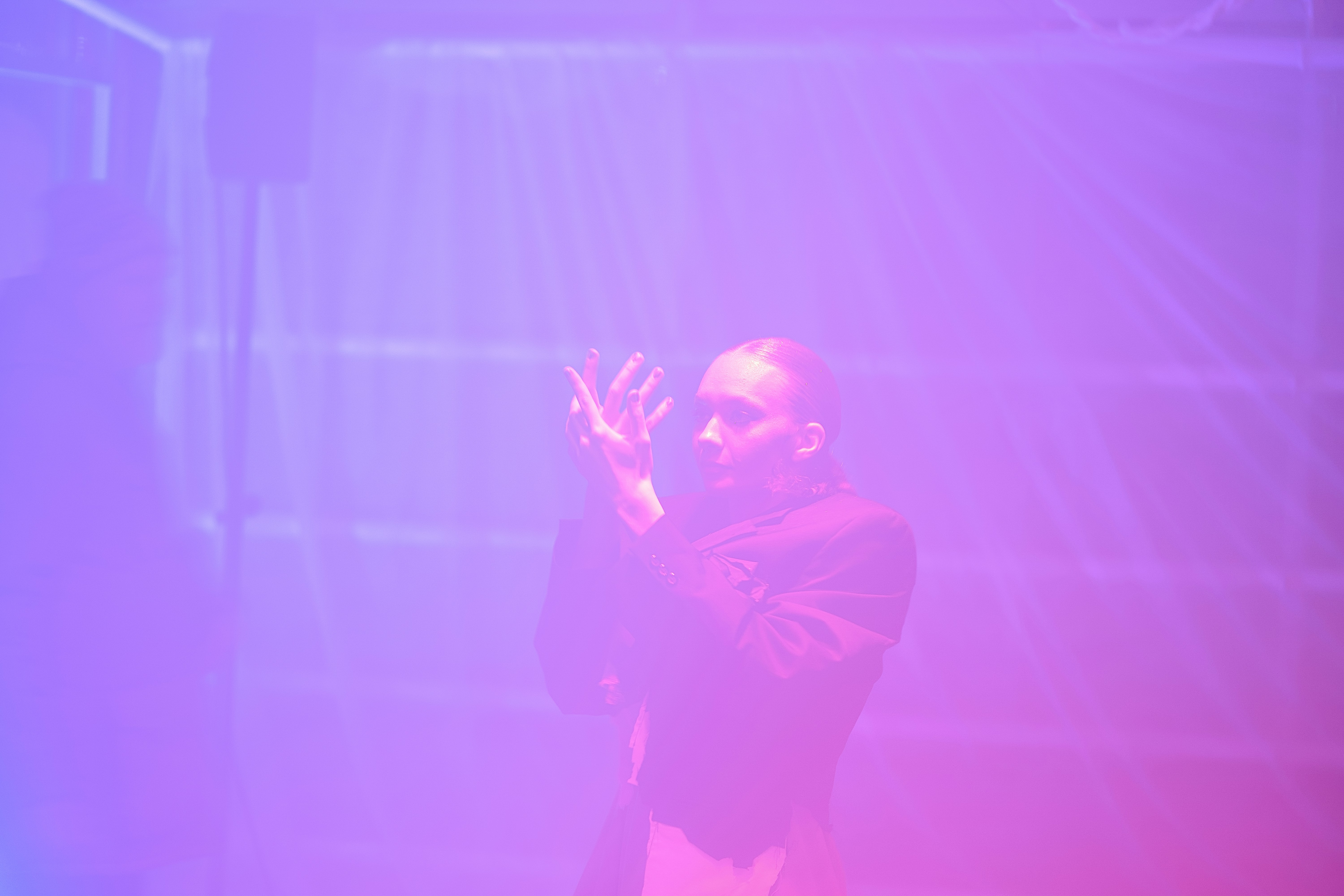 A person clapping hands in purple and pink light