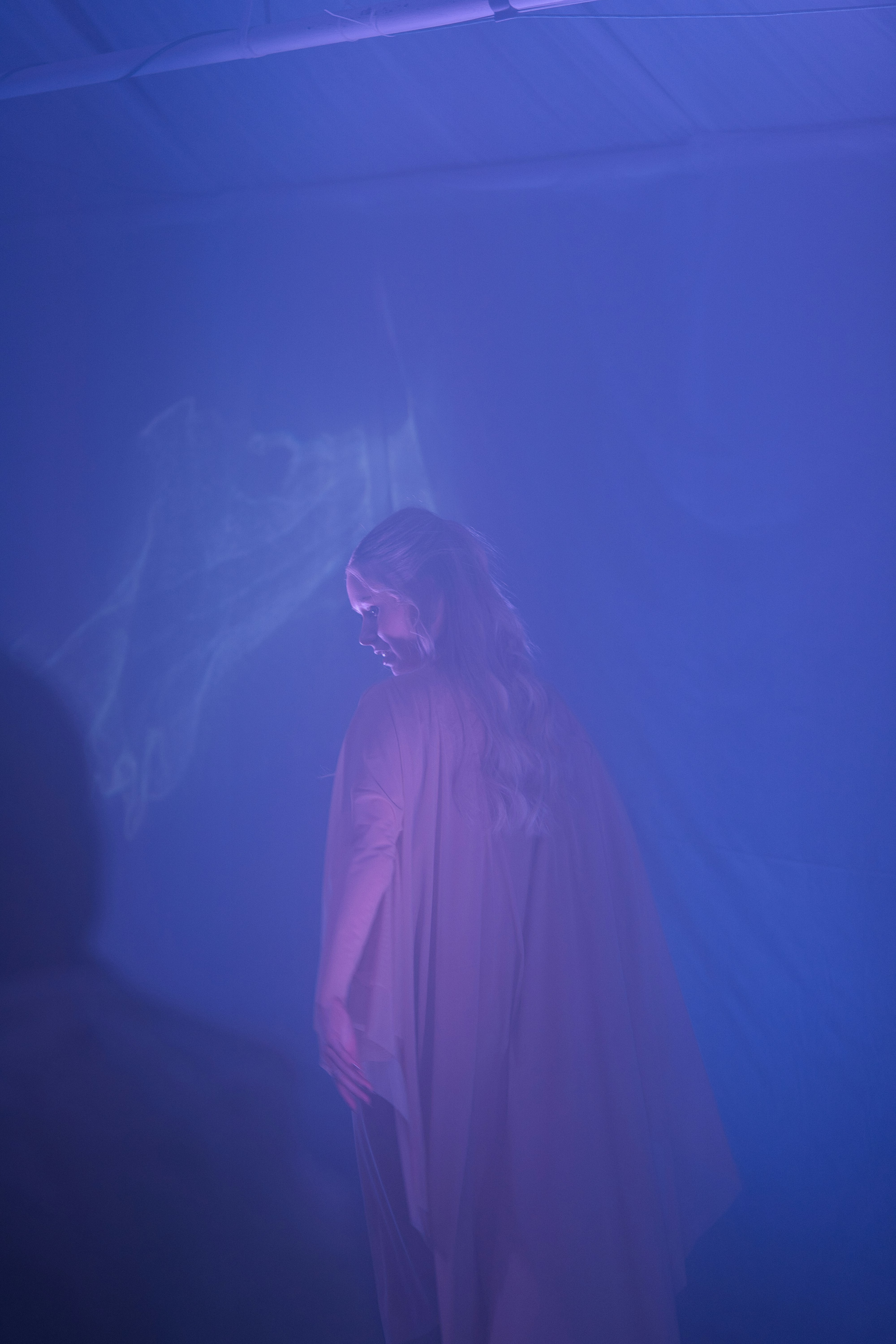 A person in a flowing garment with purple lighting.