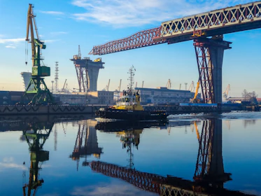 Tugboat navigates river near bridge construction site.