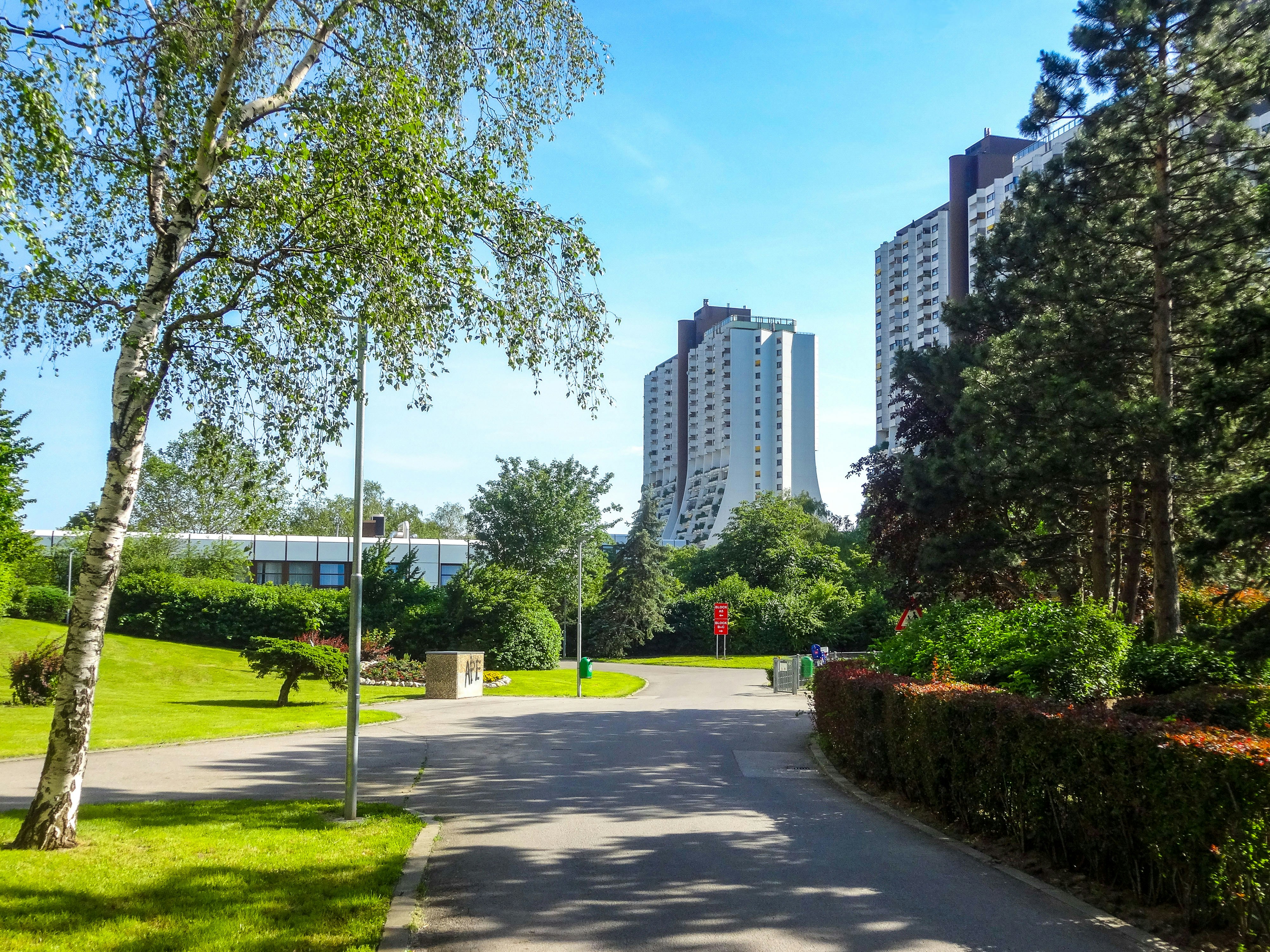 Tall apartment buildings surrounded by green trees and grass.