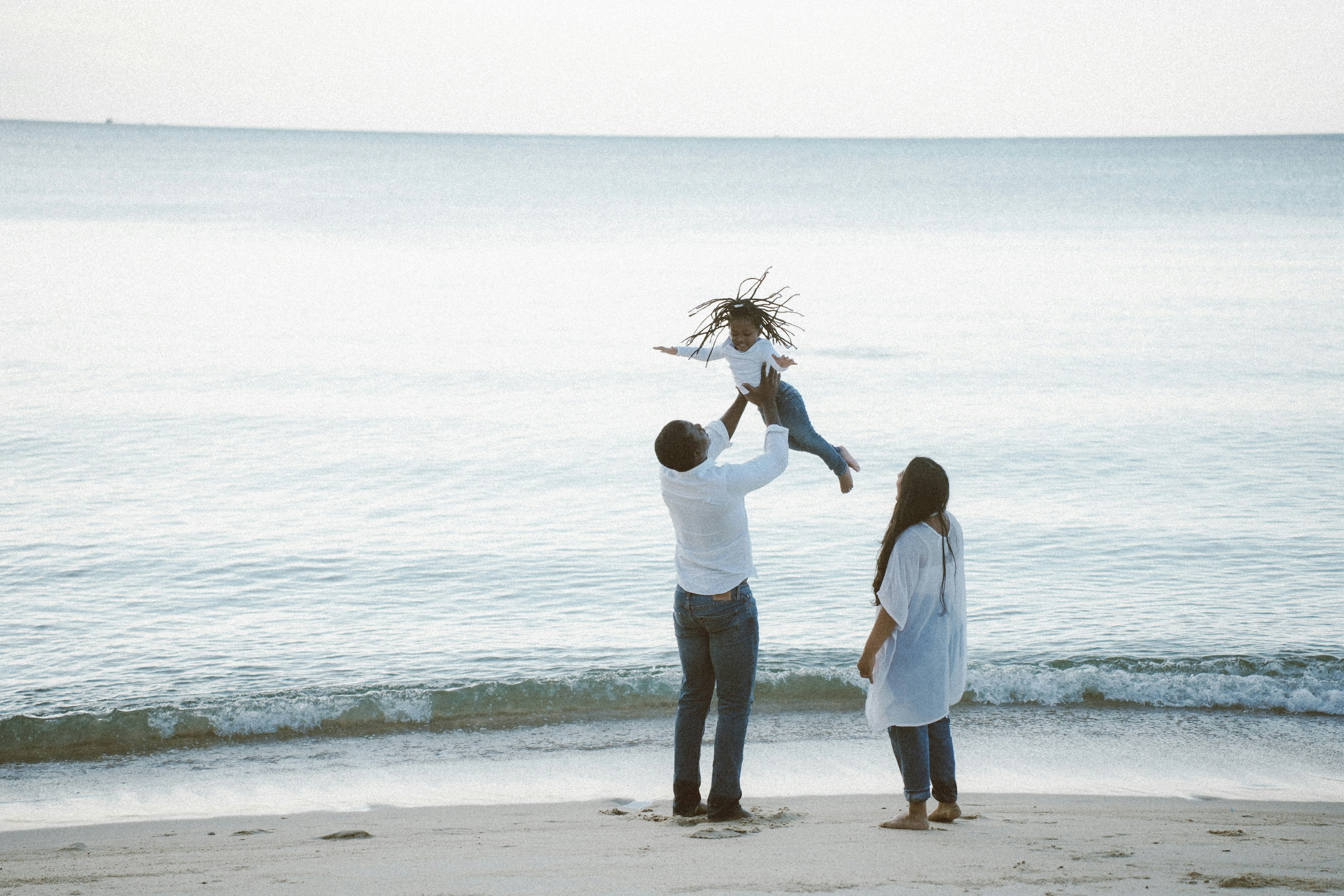 Father throws daughter in the air at beach
