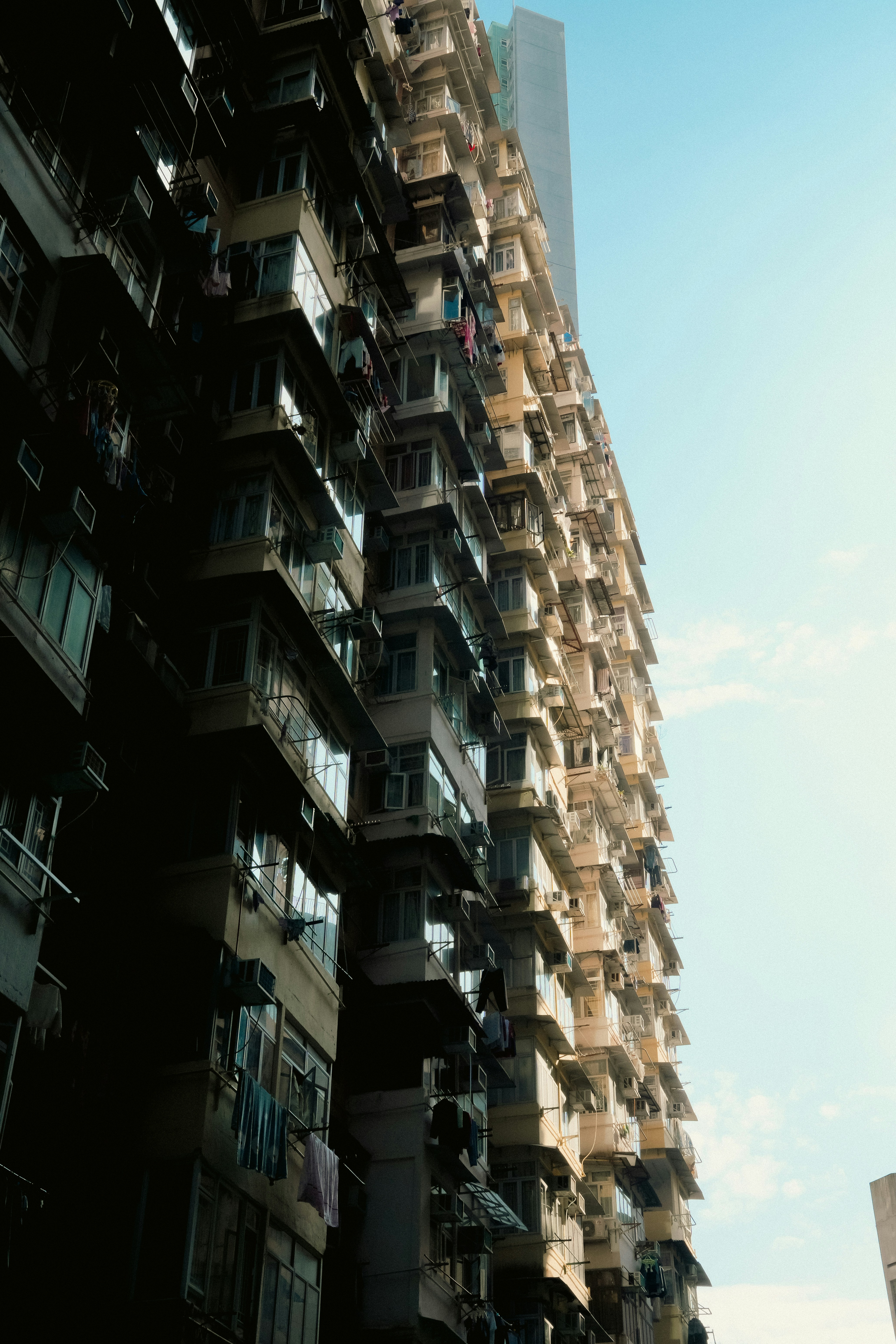 Tall apartment building with many balconies against blue sky