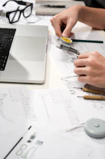 Hands measuring watch part with calipers and blueprints
