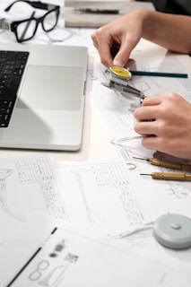 Hands measuring watch part with calipers and blueprints