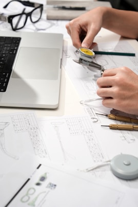 Hands measuring watch part with calipers and blueprints