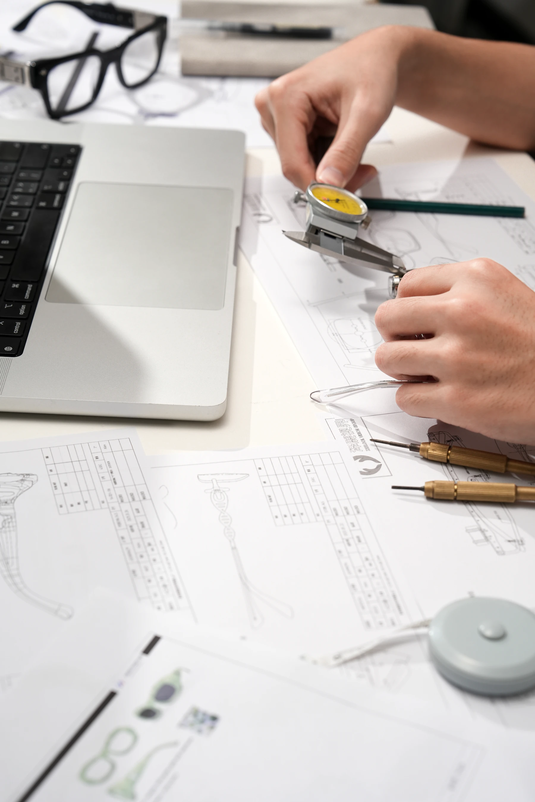 Existing component being measured with calipers over technical drawings