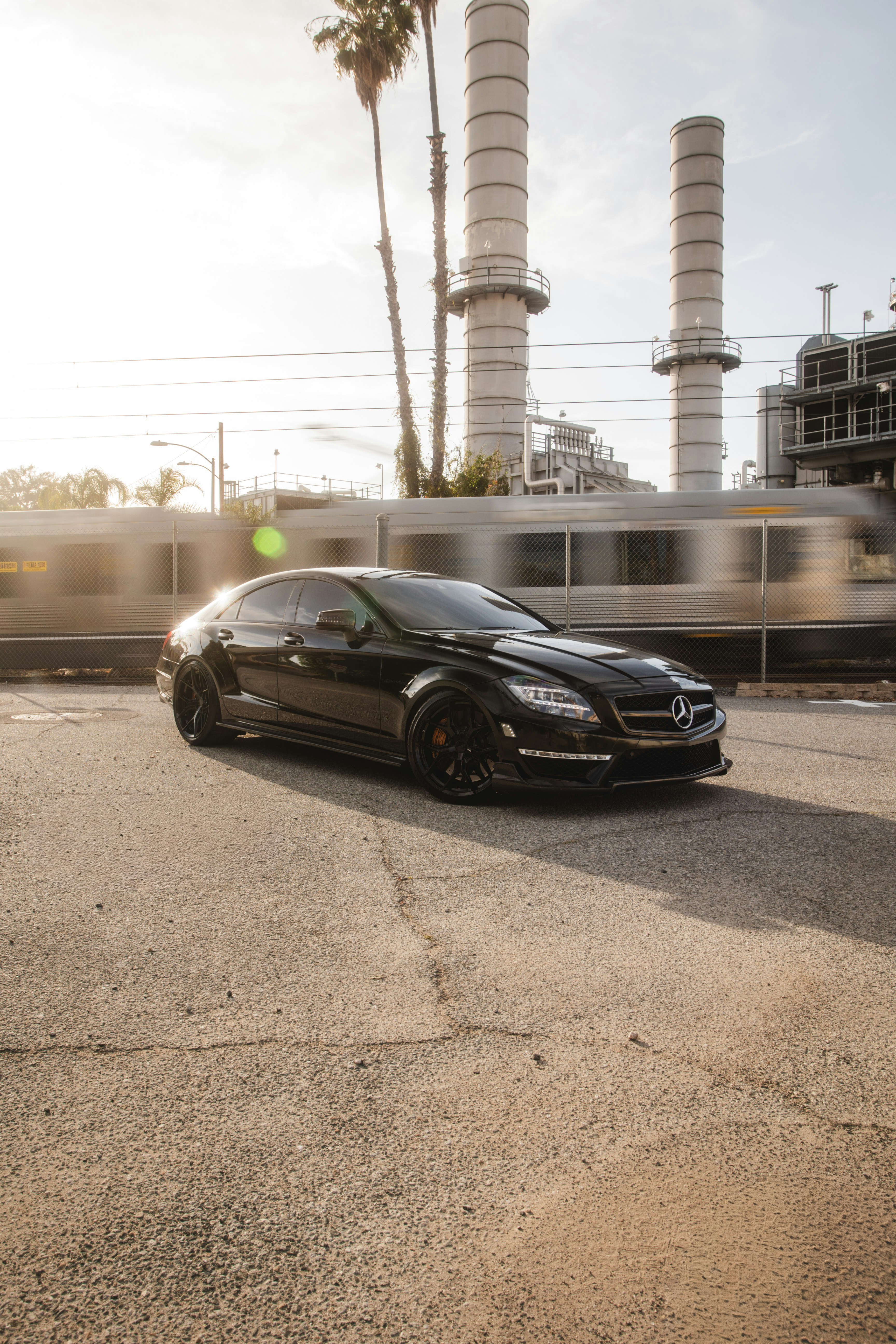 Black luxury car parked near industrial buildings and train