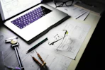 Desk with laptop, blueprints, and tools