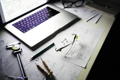 Desk with laptop, blueprints, and tools