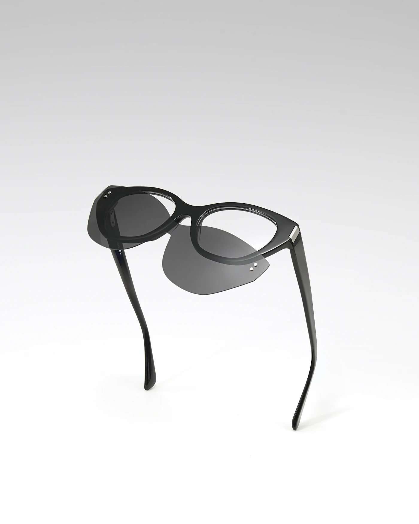 Black cat-eye sunglasses on a pale gradient background