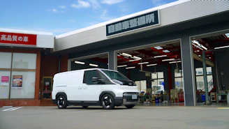 White van parked outside a building with garage doors.