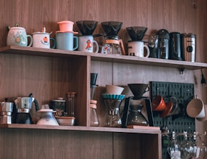 Coffee brewing equipment displayed on wooden shelves.