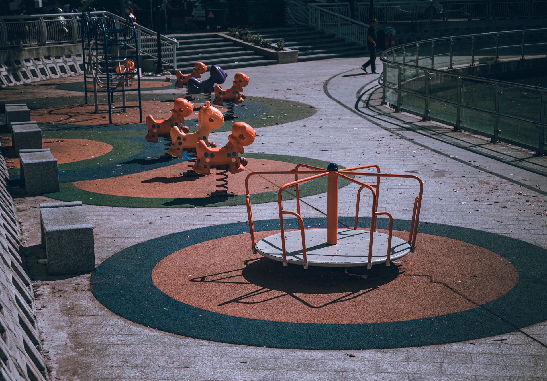 An empty playground with a merry-go-round and spring riders.