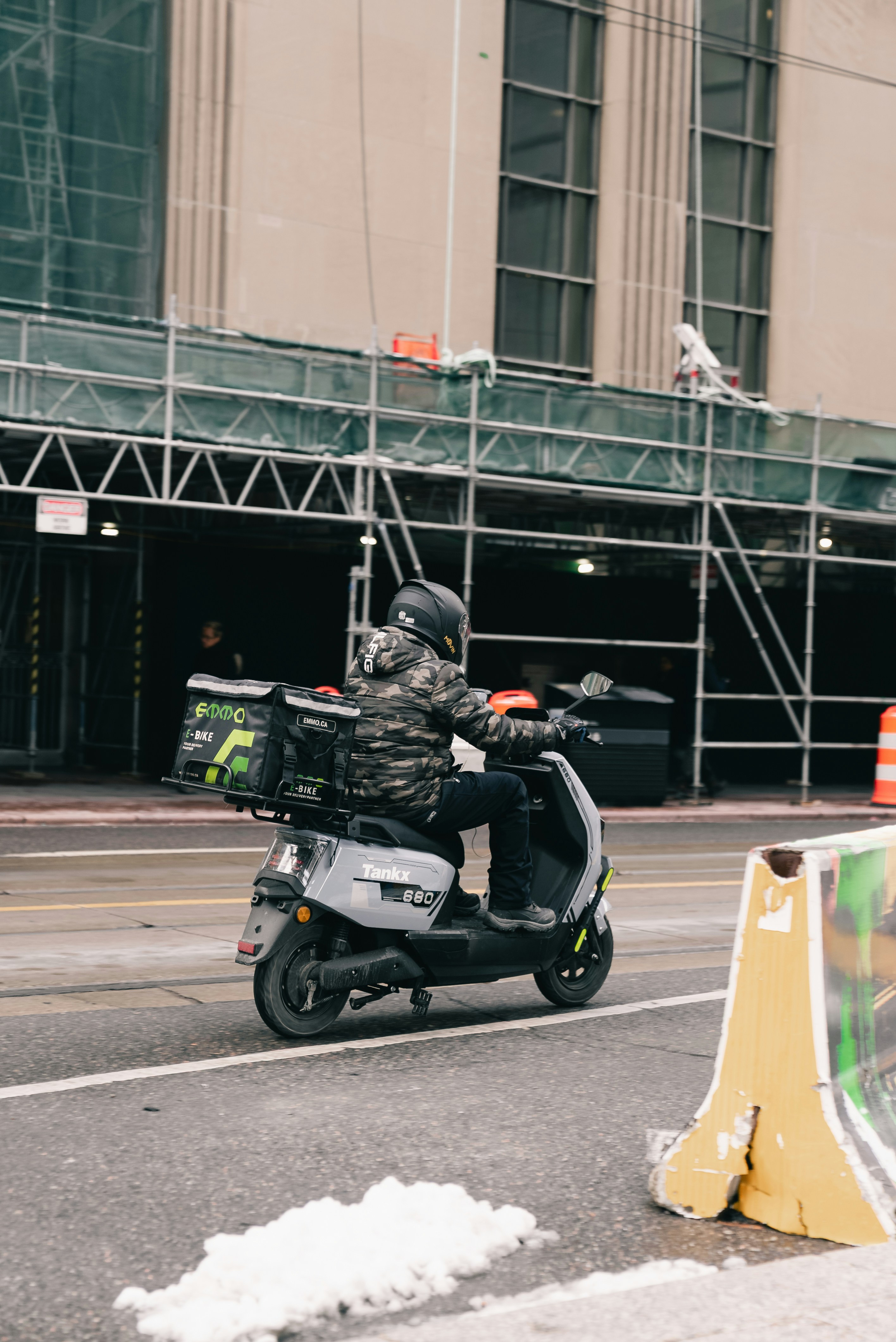 Repartidor pasa en scooter junto a la obra