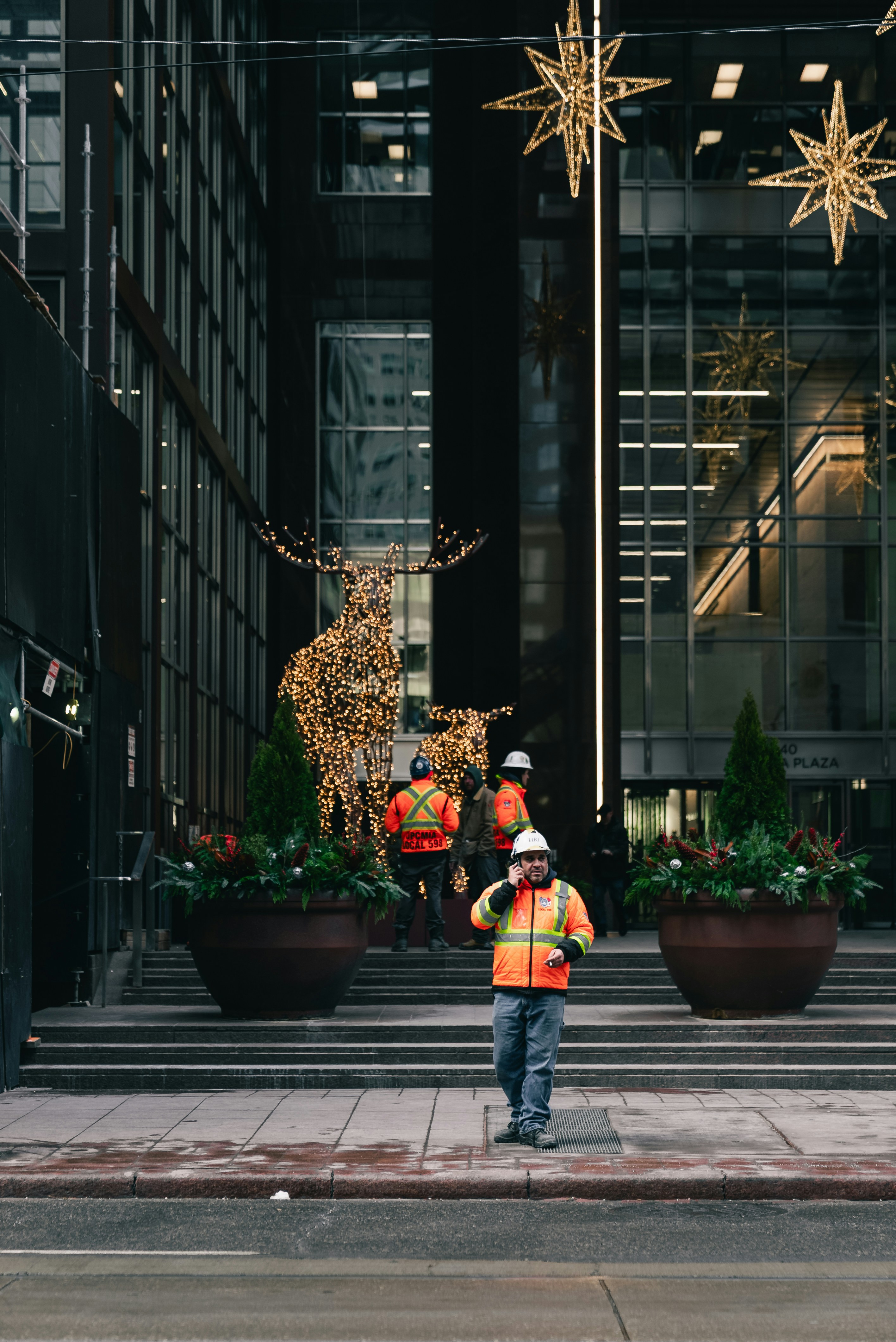 Bauarbeiter stehen in der Nähe der Festtagsdekorationen vor dem Gebäude.