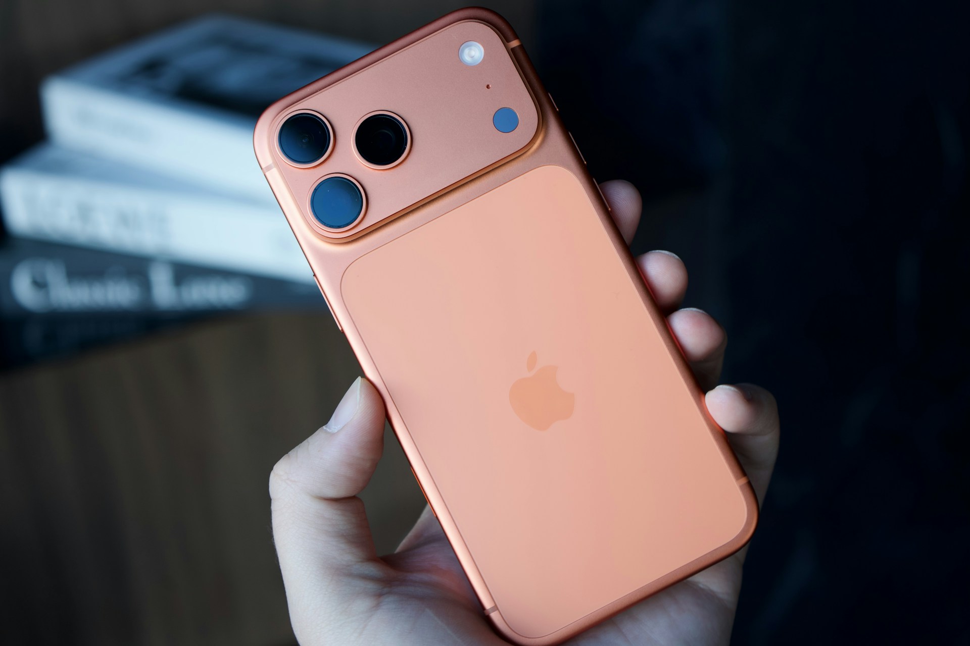Hand holding a copper-colored smartphone with dual cameras
