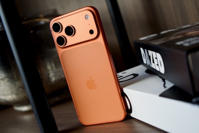 Orange smartphone with triple camera system.