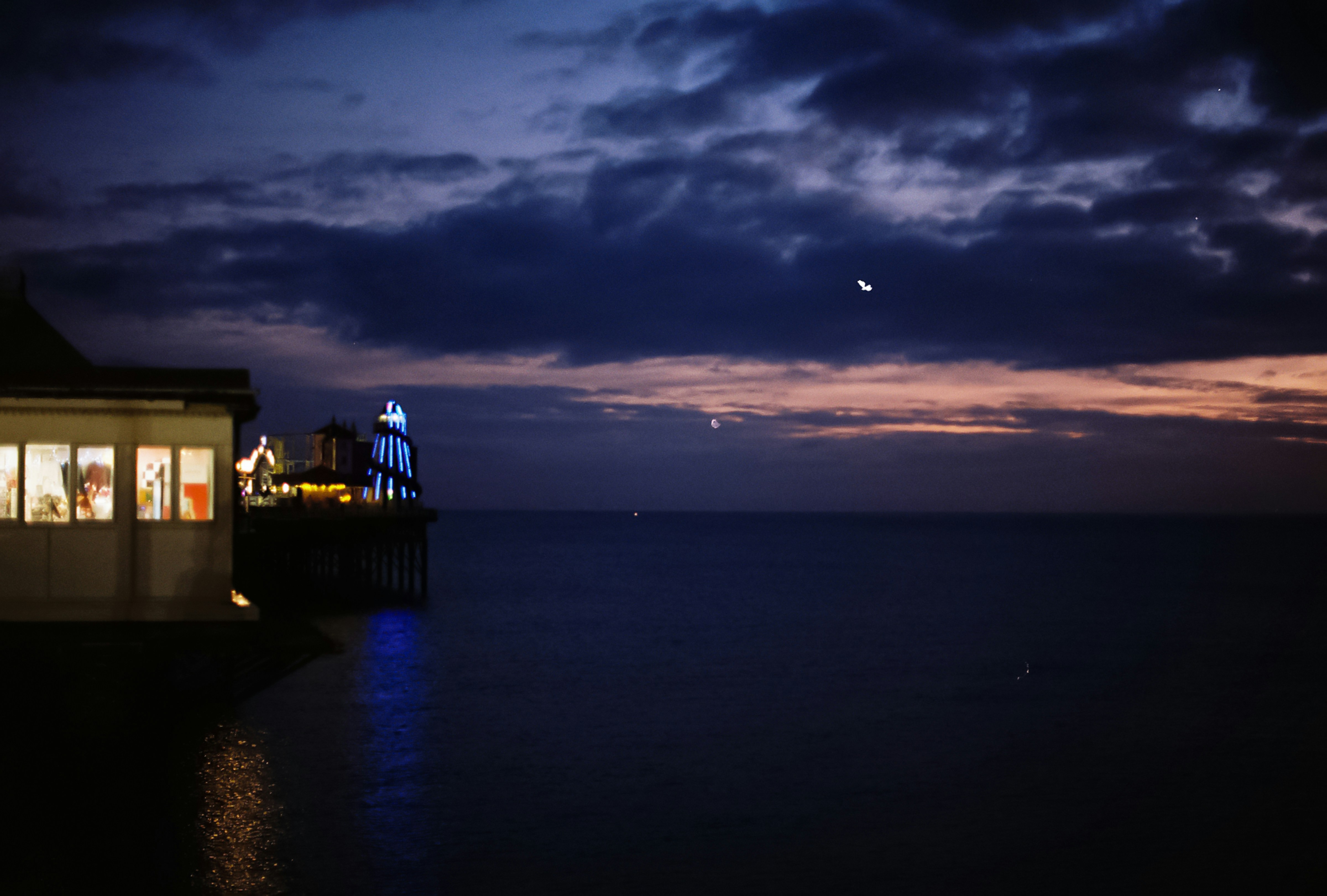 Pier building and ocean at dusk with moon