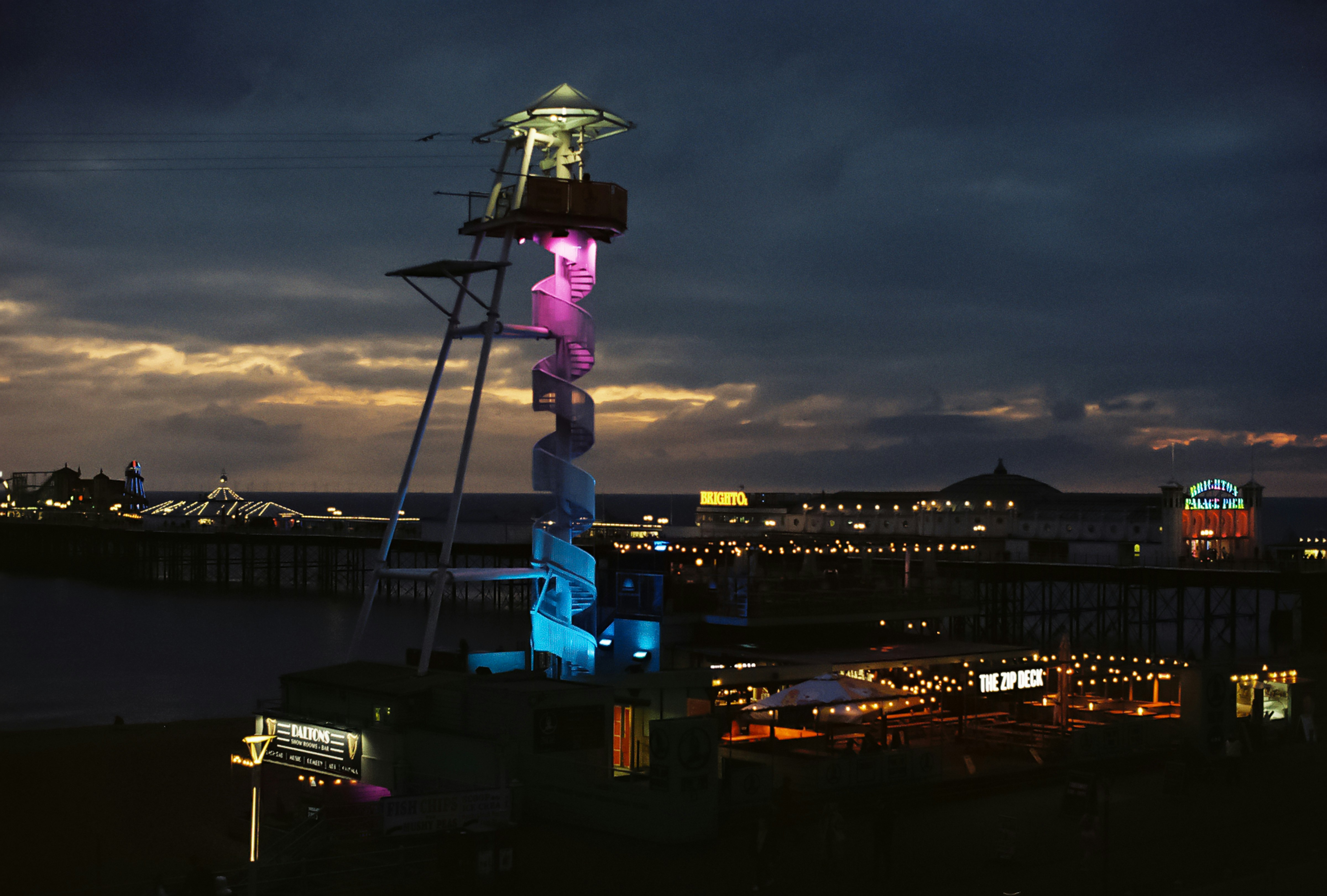 Beleuchtete Turmstruktur bei Einbruch der Dämmerung mit Pier-Hintergrund