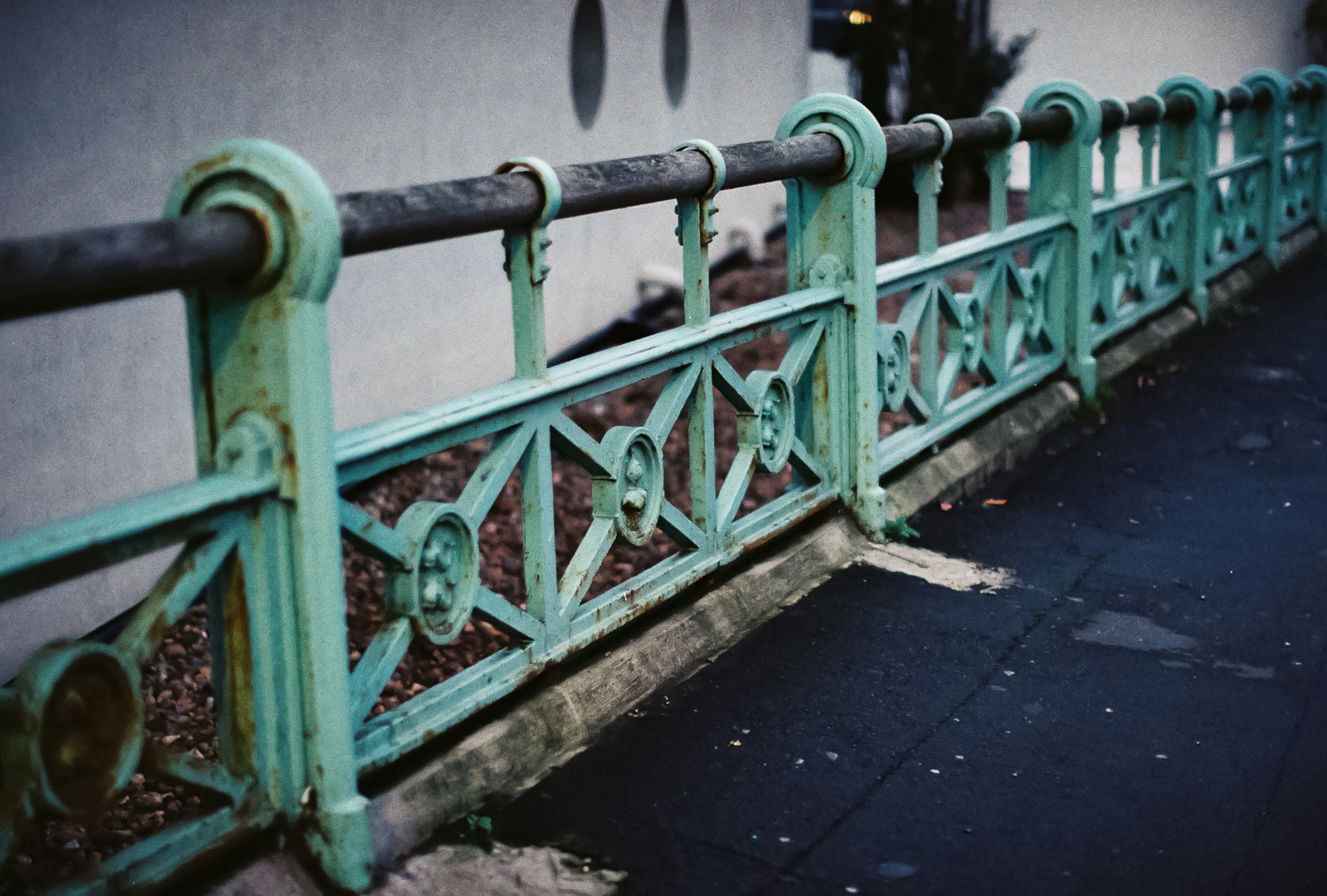 Ornate green metal fence with weathered texture.