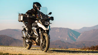 Motorcyclist riding on a dirt road with mountains behind