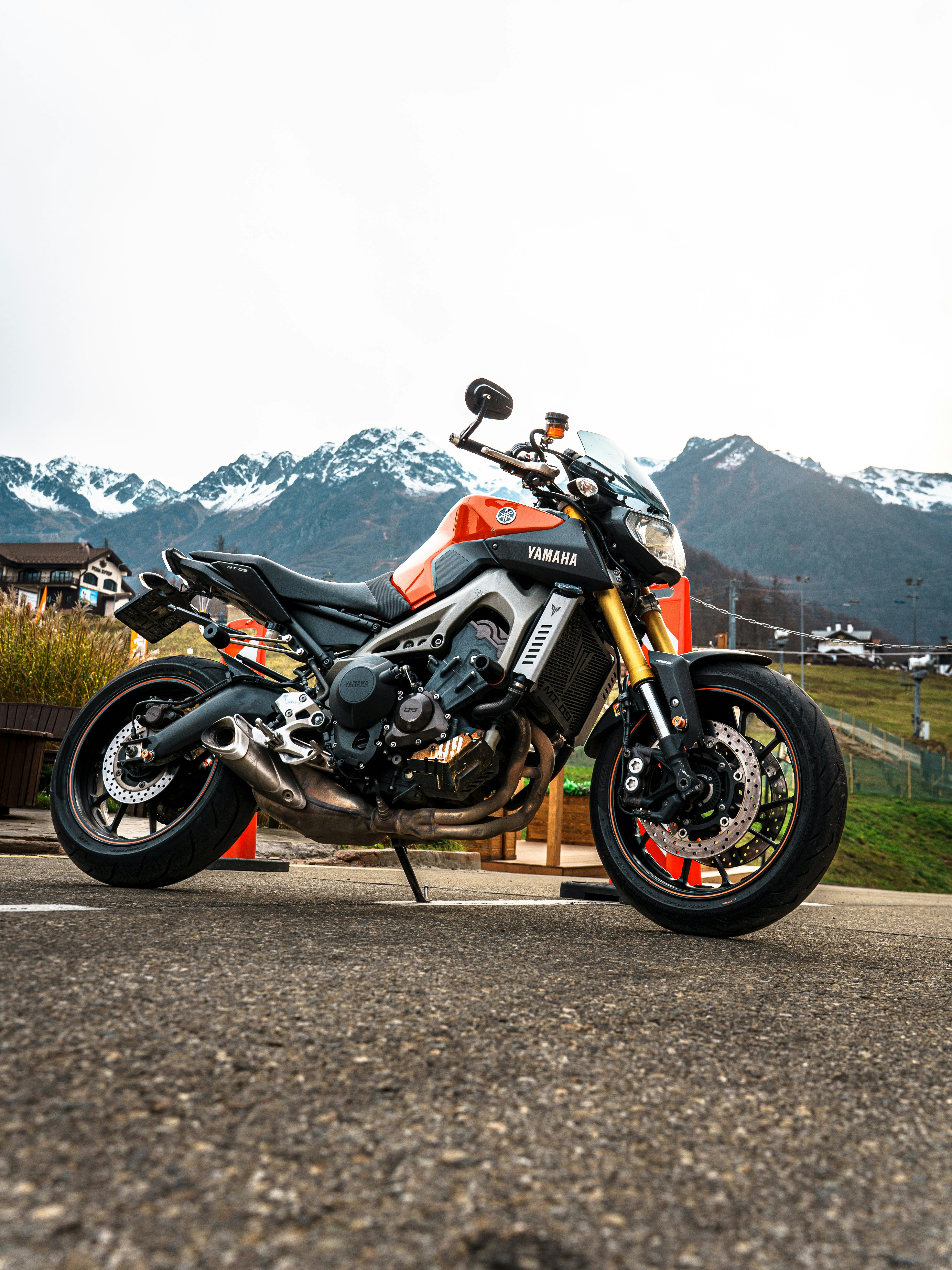 Orange and black motorcycle parked outdoors with mountains