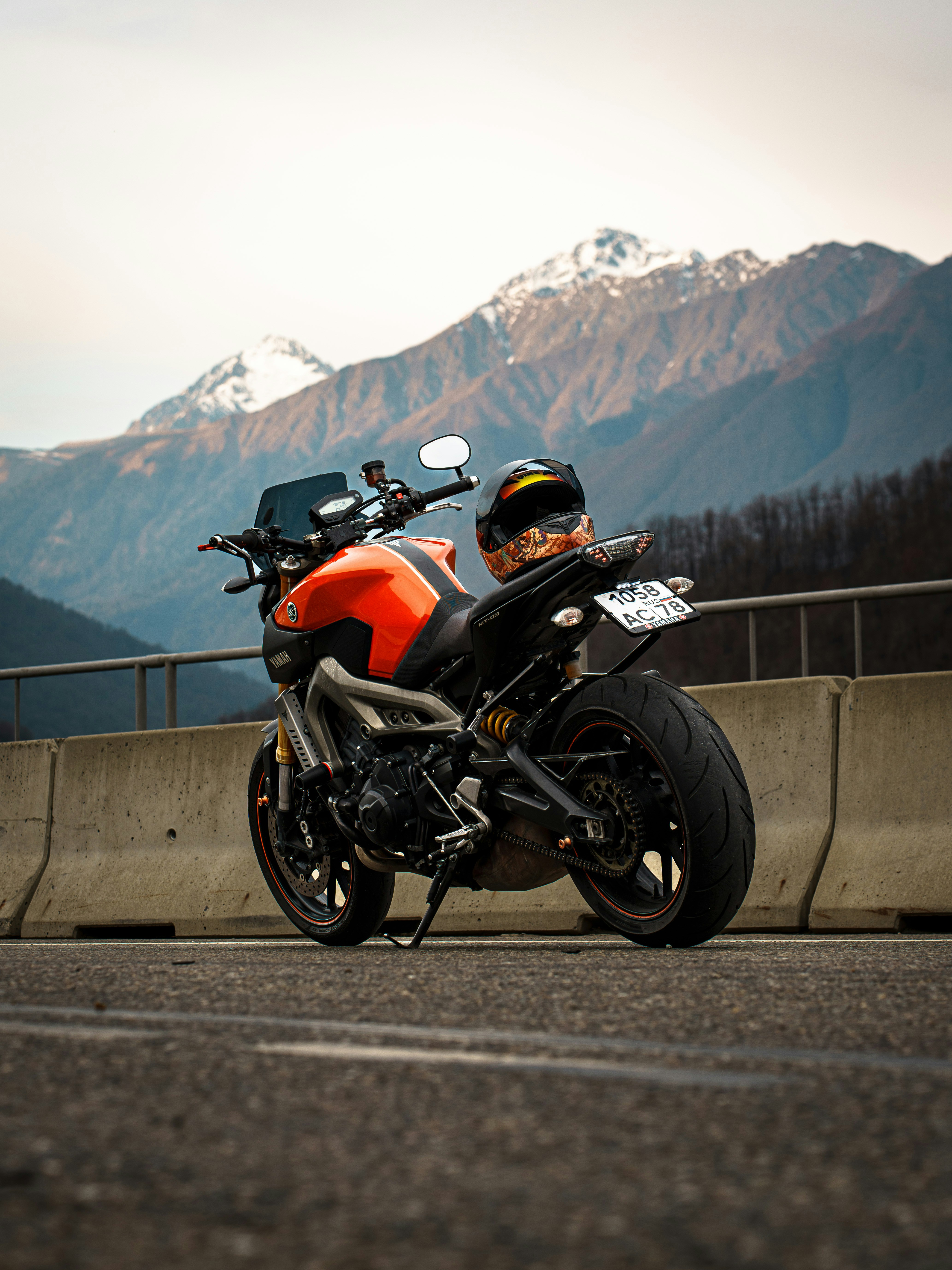 Orange motorcycle parked on a road with mountains