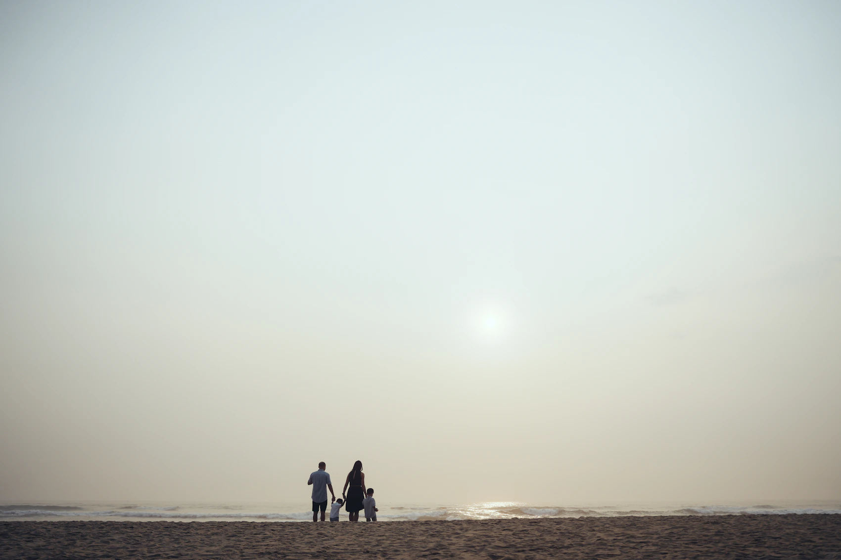 A family walking together along the shore at sunset