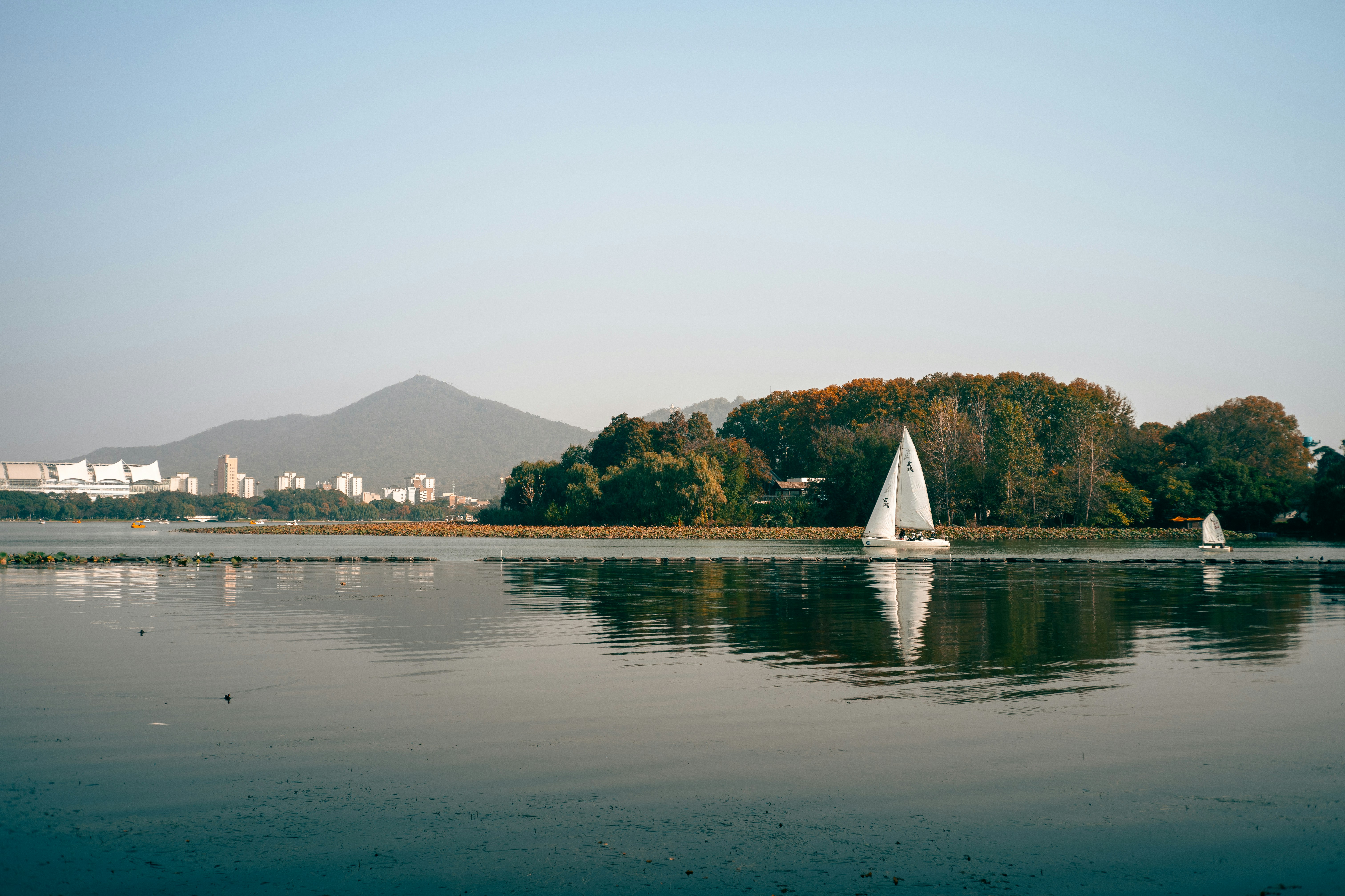 遠くの丘が広がる穏やかな湖の上のヨット。
