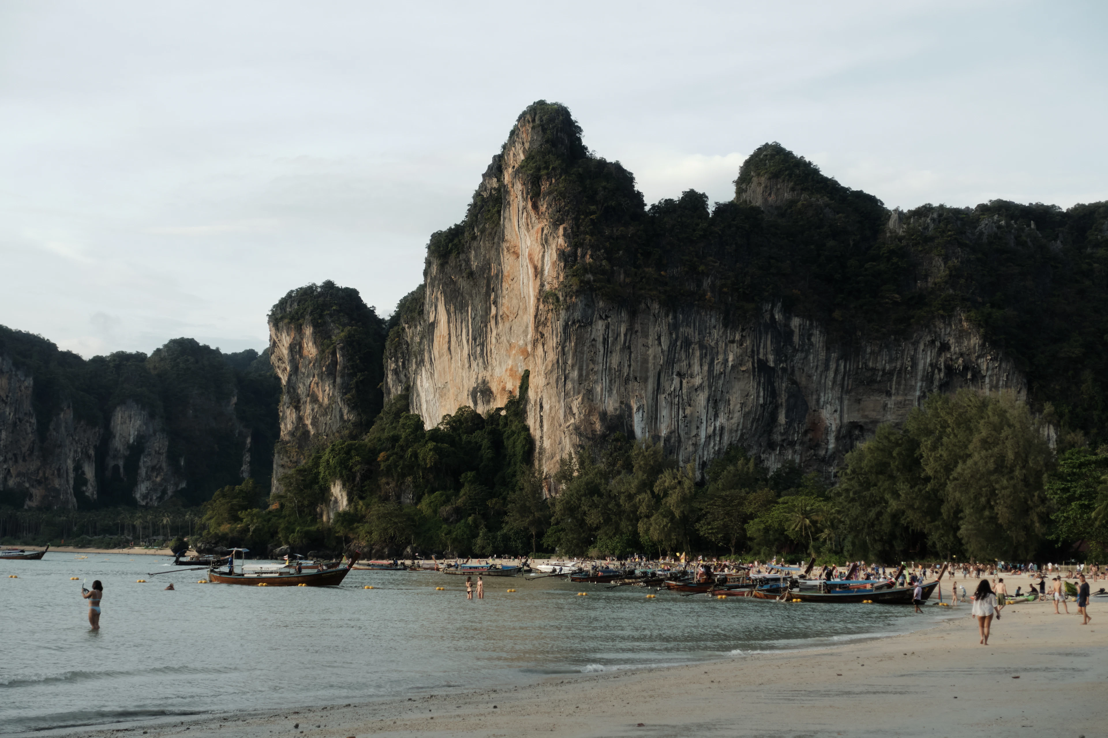 Longtail boats beneath the limestone cliffs of Railay Beach in Thailand