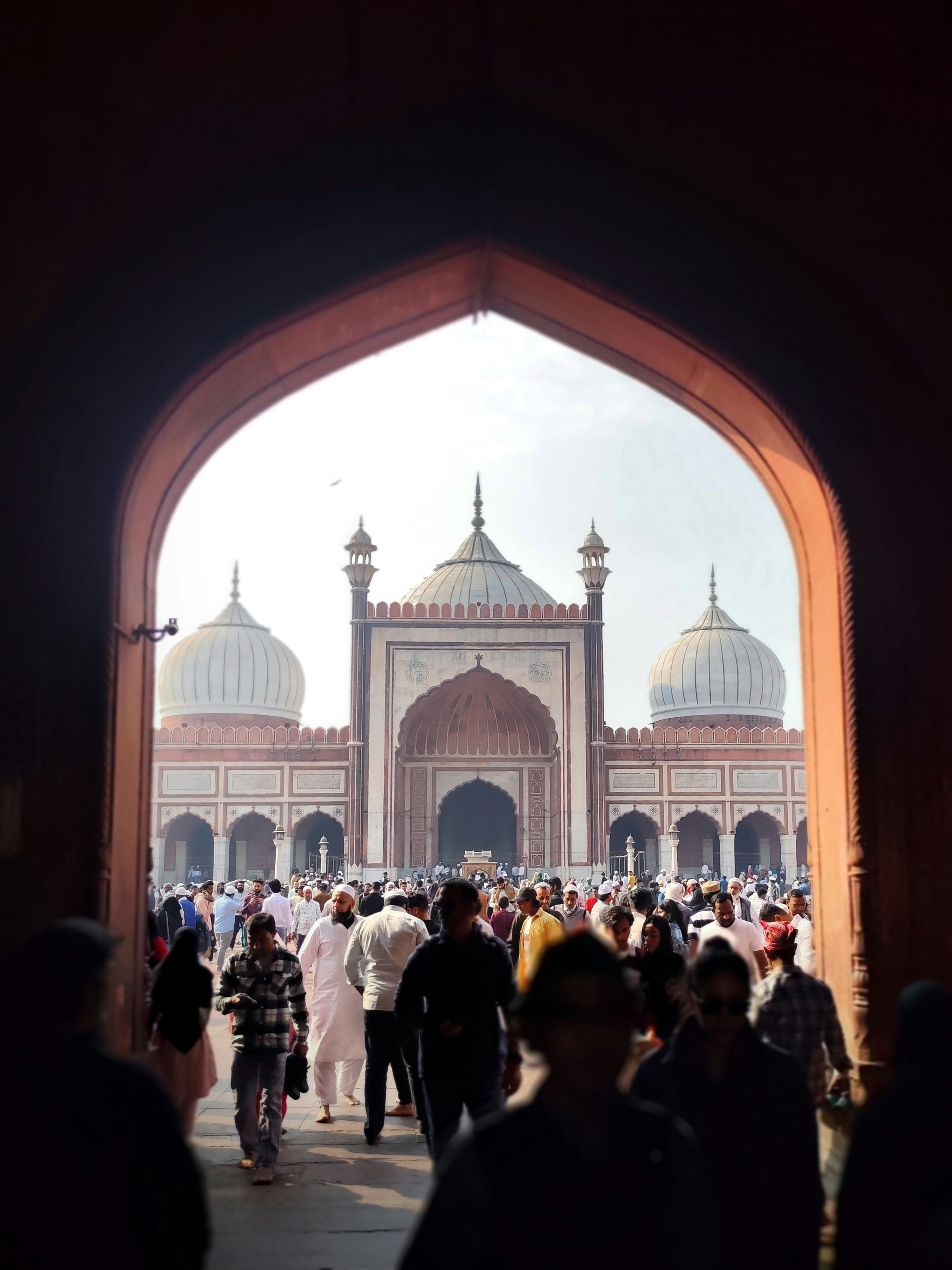 People entering a large mosque with domes and minarets.