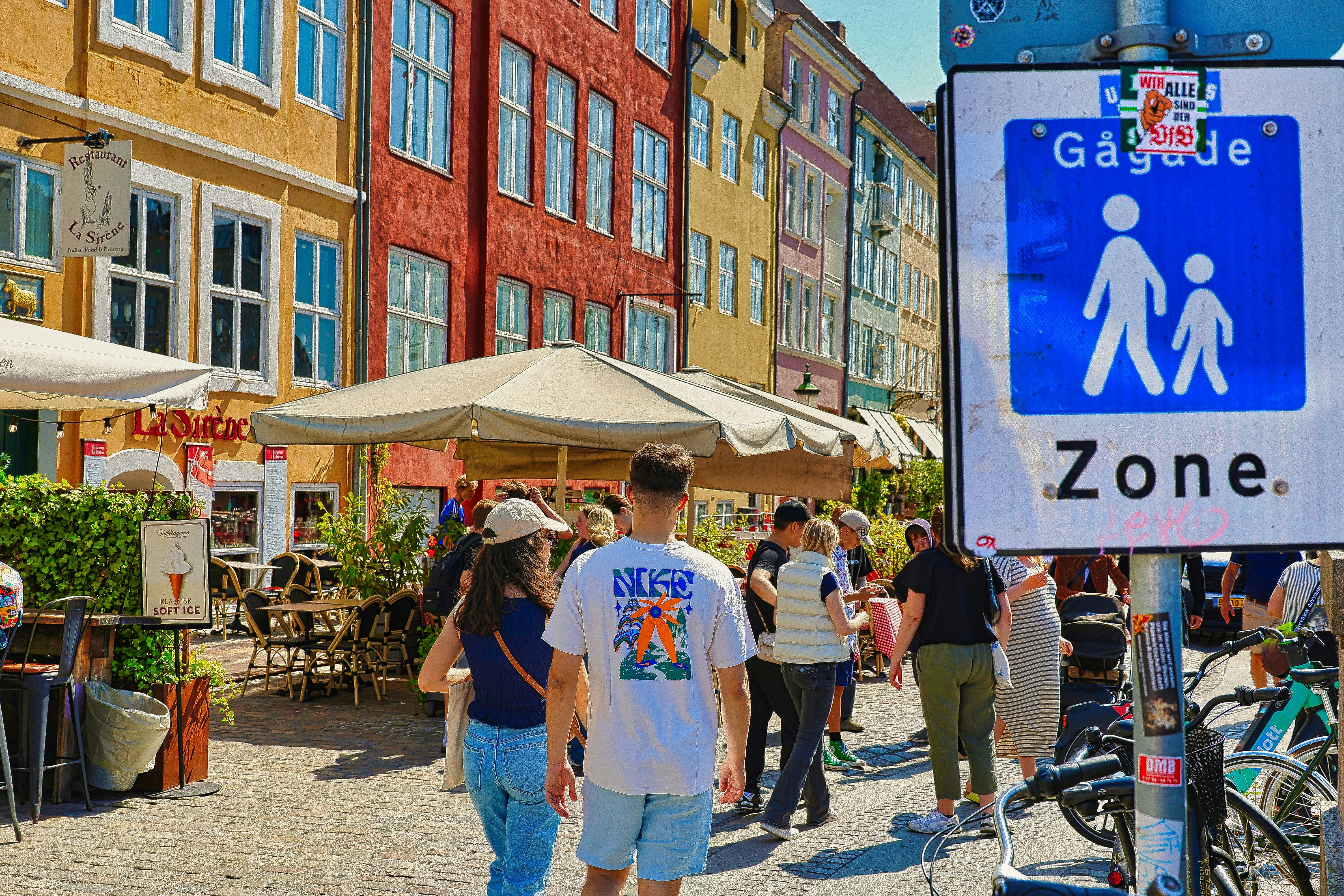 People walking in a European pedestrian zone with colorful buildings.