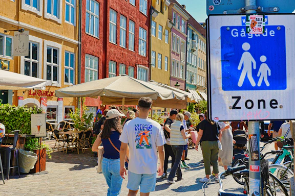 People walking in a pedestrian zone with colorful buildings.