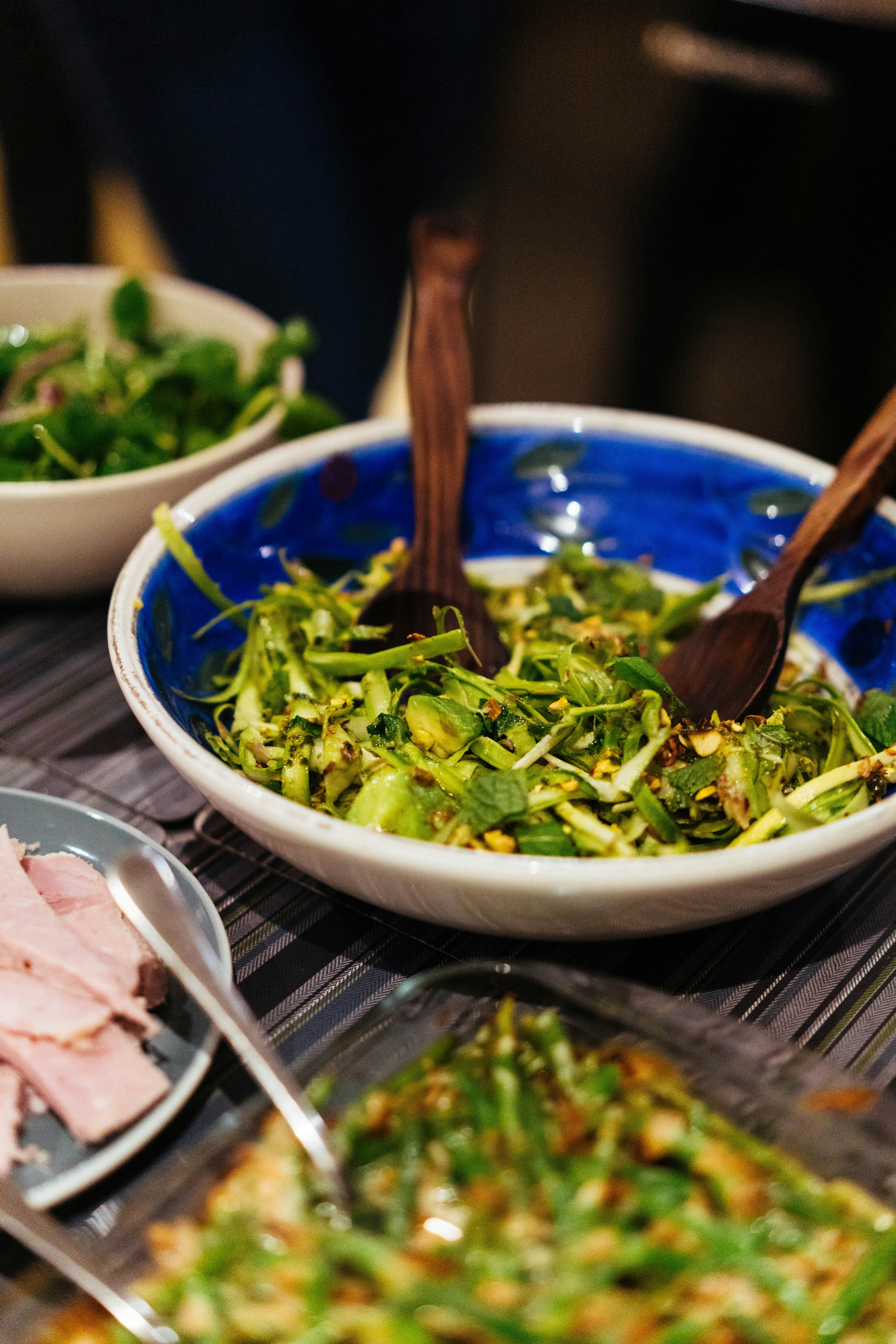 Fresh green salad in a blue bowl with wooden spoons