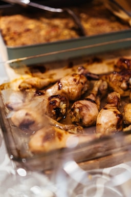 Roasted chicken drumsticks in a glass baking dish.